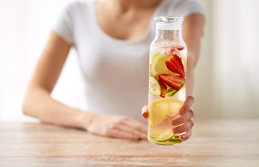 Image showing close up of woman with fruit water in glass bottle