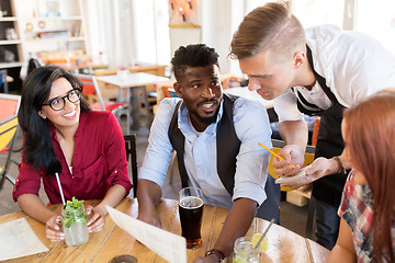 Image showing waiter and friends with menu and drinks at bar