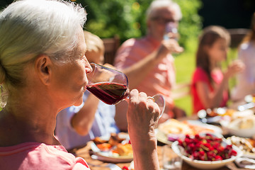 Image showing senior woman drinking wine at family dinner