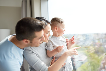 Image showing happy family looking through window at home