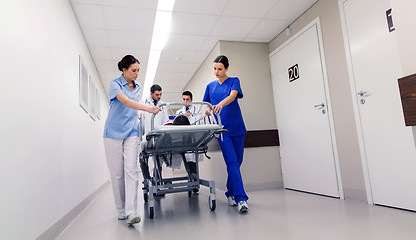 Image showing medics with woman on hospital gurney at emergency