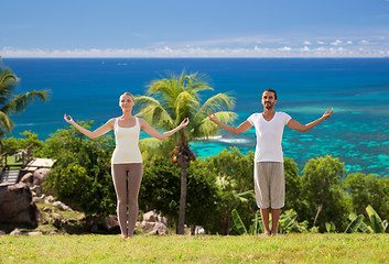 Image showing happy couple making yoga exercises on beach