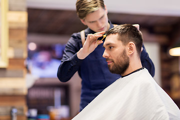 Image showing man and barber cutting hair at barbershop