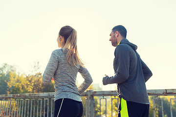 Image showing happy couple with earphones running outdoors