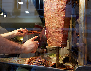Image showing An arm moving to cut the kebab meat