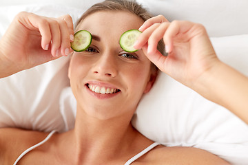 Image showing beautiful woman applying cucumbers to eyes at home