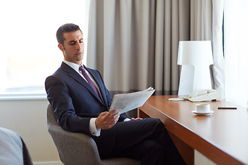 Image showing businessman reading newspaper at hotel room