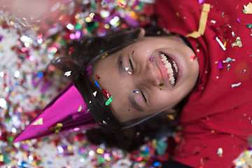 Image showing kid blowing confetti while lying on the floor