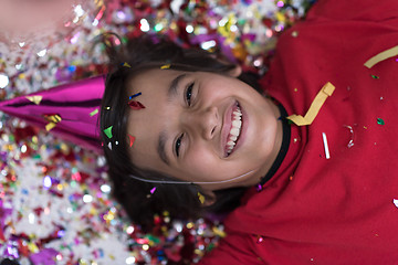 Image showing kid blowing confetti while lying on the floor