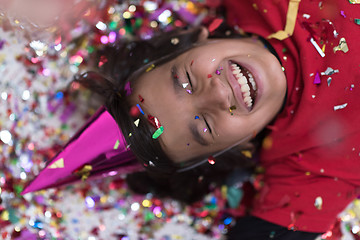 Image showing kid blowing confetti while lying on the floor