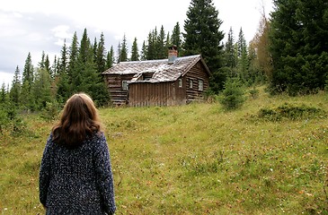 Image showing Woman looking at old cottage