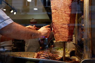 Image showing An arm moving to cut the kebab meat