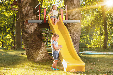 Image showing Happy little girls rolling down the hill on the playground