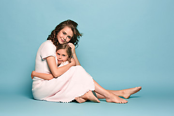 Image showing Pregnant mother with teen daughter. Family studio portrait over blue background