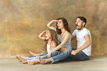 Image showing Pregnant mother with teen daughter and husband. Family studio portrait over brown background