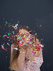 Image showing woman blowing confetti in the air isolated over gray