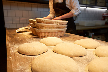 Image showing baker with baskets for dough rising at bakery