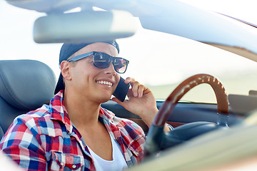 Image showing young man driving car and calling on smartphone