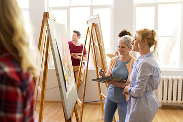 Image showing artists discussing painting on easel at art school