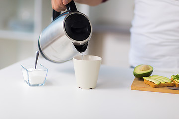 Image showing man with kettle making tea for breakfast at home