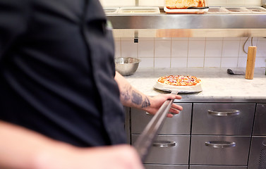 Image showing cook or baker with pizza on peel at pizzeria