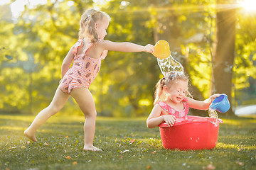 Image showing The cute little blond girls playing with water splashes on the field in summer