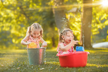 Image showing The cute little blond girls playing with water splashes on the field in summer