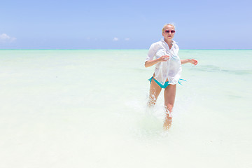 Image showing Young active woman having fun running and splashing in shellow sea water.
