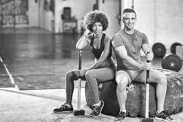 Image showing multiethnic couple after workout with hammer