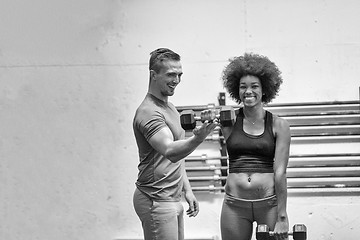 Image showing black woman doing bicep curls with fitness trainer