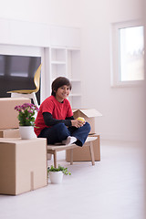 Image showing boy sitting on the table with cardboard boxes around him