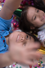 Image showing kids  blowing confetti while lying on the floor