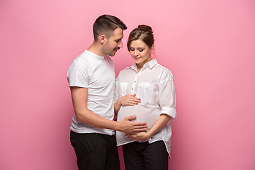 Image showing Handsome man is listening to his beautiful pregnant wife\'s tummy and smiling