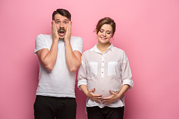 Image showing The funny surprised handsome man and his beautiful pregnant wife\'s tummy