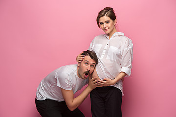 Image showing Handsome man is listening to his beautiful pregnant wife\'s tummy and smiling