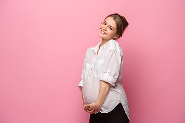 Image showing Young beautiful pregnant woman standing on pink background