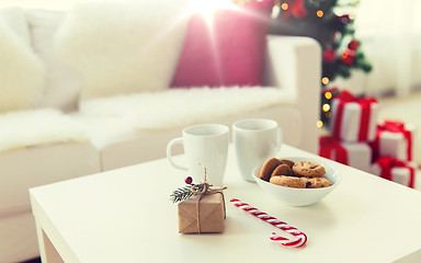 Image showing close up of gift, sweets and cups on table at home