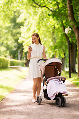 Image showing happy mother with smartphone and stroller at park