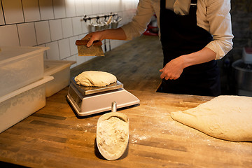 Image showing baker weighing bread dough on scale at bakery