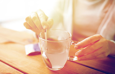 Image showing woman stirring medication in cup of water