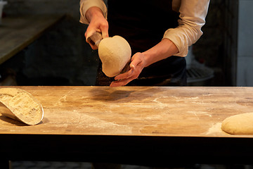 Image showing baker portioning dough with bench cutter at bakery