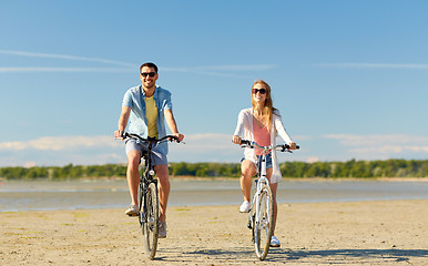 Image showing happy young couple riding bicycles at seaside