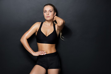 Image showing young woman in black sportswear posing in gym