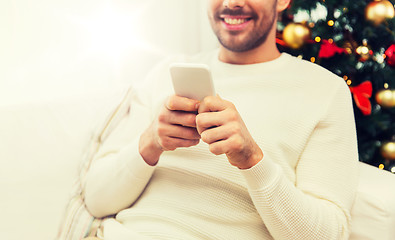 Image showing smiling man with smartphone at home for christmas