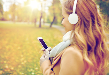 Image showing woman with smartphone and earphones in autumn park