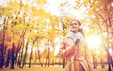 Image showing woman with smartphone and earphones in autumn park