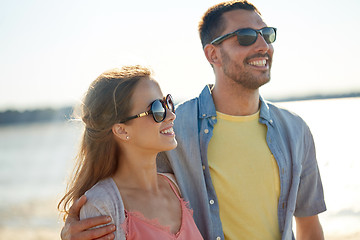 Image showing happy couple in sunglasses hugging on summer beach