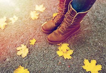 Image showing female feet in boots and autumn leaves