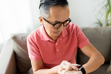 Image showing close up of asian man with smart watch at home