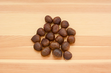 Image showing Sweet chestnuts in shells on wood